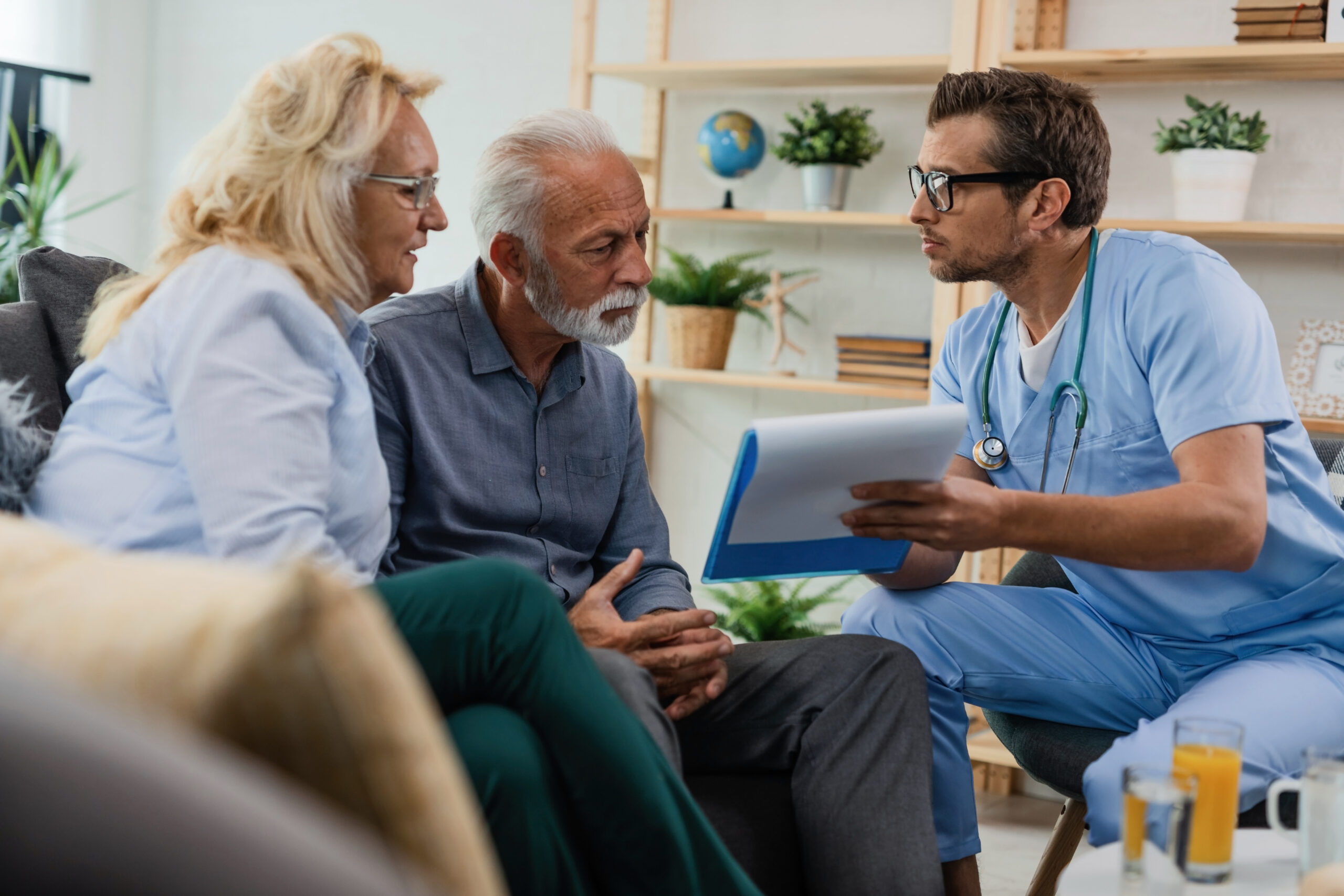 Home health clinician reviewing documents with a senior couple during a home visit